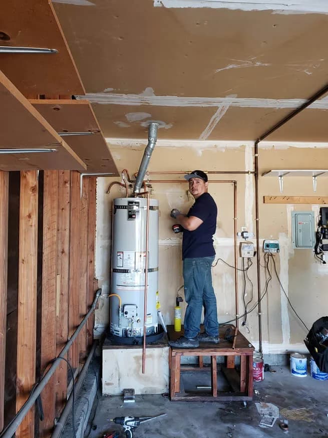 A person working beside a tank water heater in the published BWH project gallery